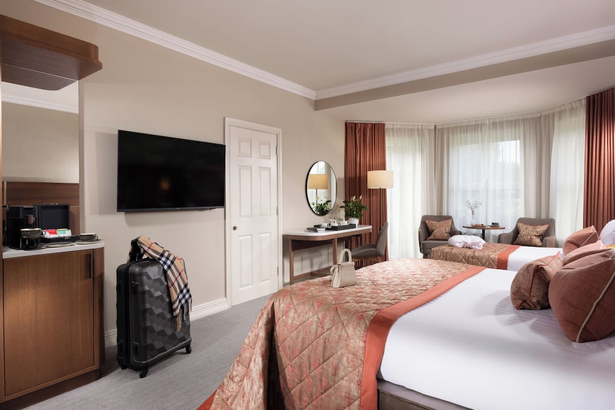 A hotel room with a bed, a desk, a TV, and a suitcase.