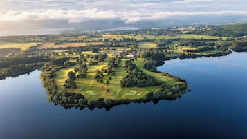 Eine Insel mit einem Golfplatz, umgeben von Wasser, mit einem großen Haus in der Mitte.