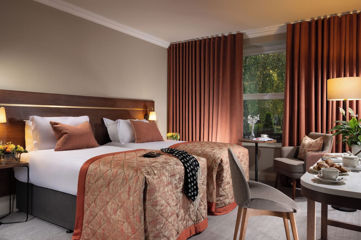 A hotel room with a large bed, a desk, and a dining table.