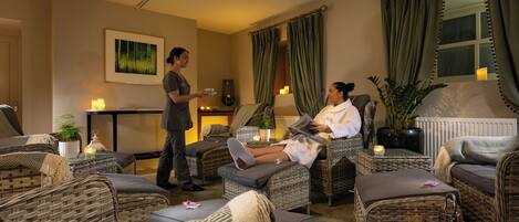 A spa-like setting with wicker furniture, a massage table, and a person reading a book.