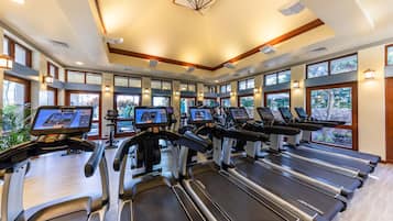 Un gimnasio con múltiples cintas de correr y máquinas de ejercicio, ventanas amplias y un diseño de techo moderno.