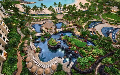 A resort with multiple swimming pools, palm trees, and a beach.