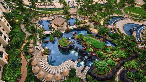 A resort with multiple swimming pools, palm trees, and a beach.