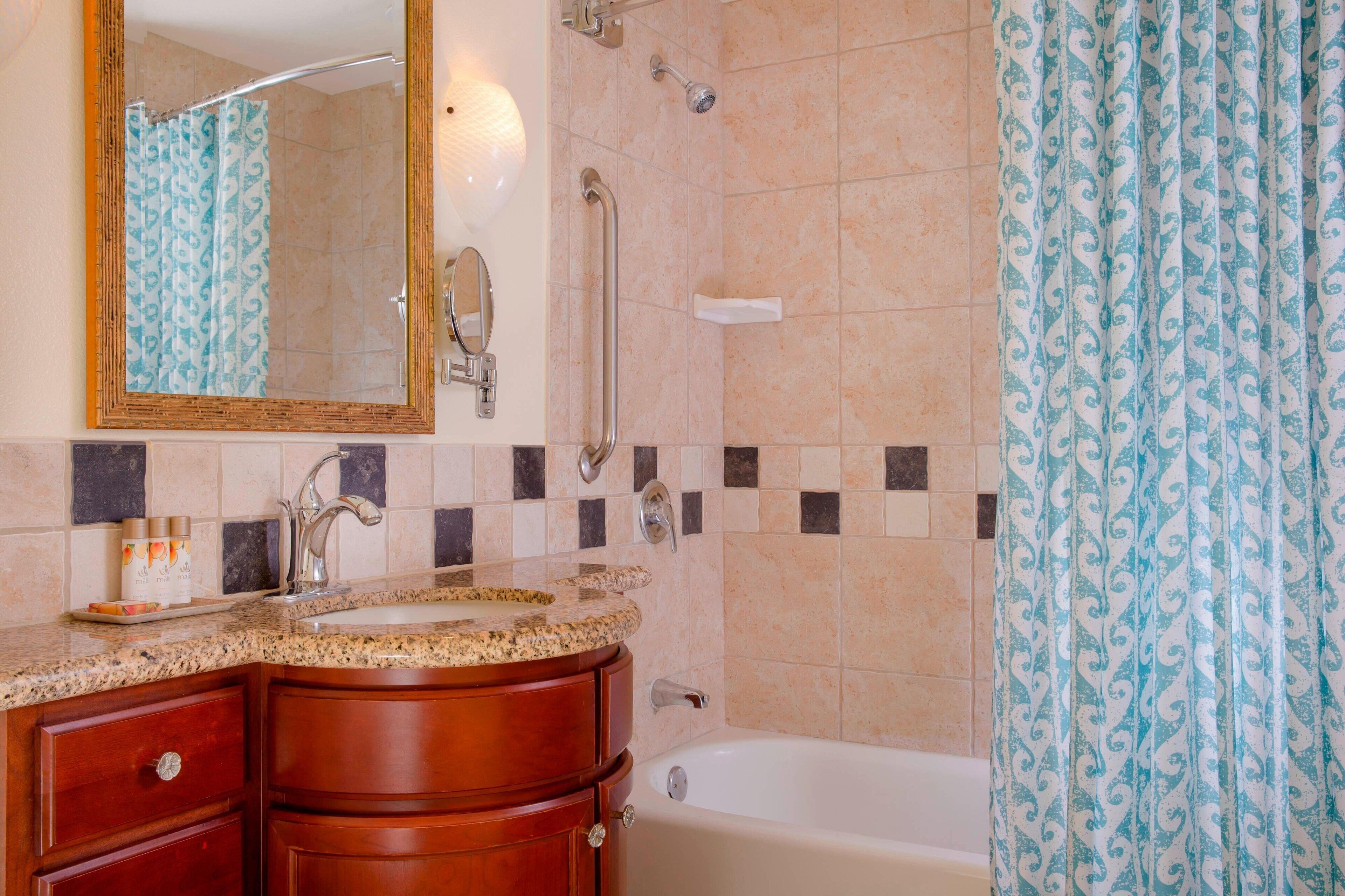 Un baño con lavamanos, espejo, tocador, ducha y bañera.