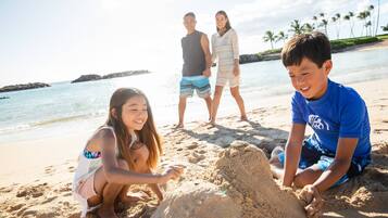 Escena de playa con gente construyendo un castillo de arena.