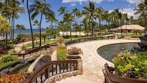 A resort with a pool, palm trees, and a view of the ocean.