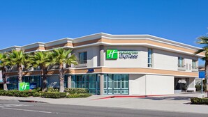 A Holiday Inn Express building with a modern design, featuring a prominent 'H' logo, large windows, and palm trees in front. - Holiday Inn Express Newport Beach by IHG (Newport Beach)