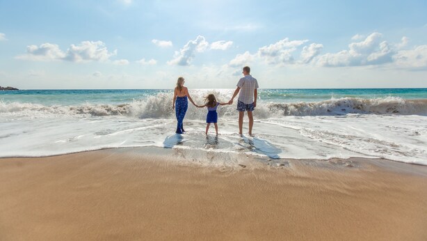 A beach scene with a family holding hands.