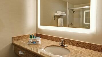 A bathroom with a granite countertop, a sink, a mirror, and a shower visible in the reflection.