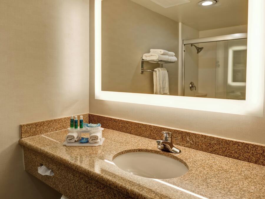 A bathroom with a granite countertop, a sink, a mirror, and a shower visible in the reflection.