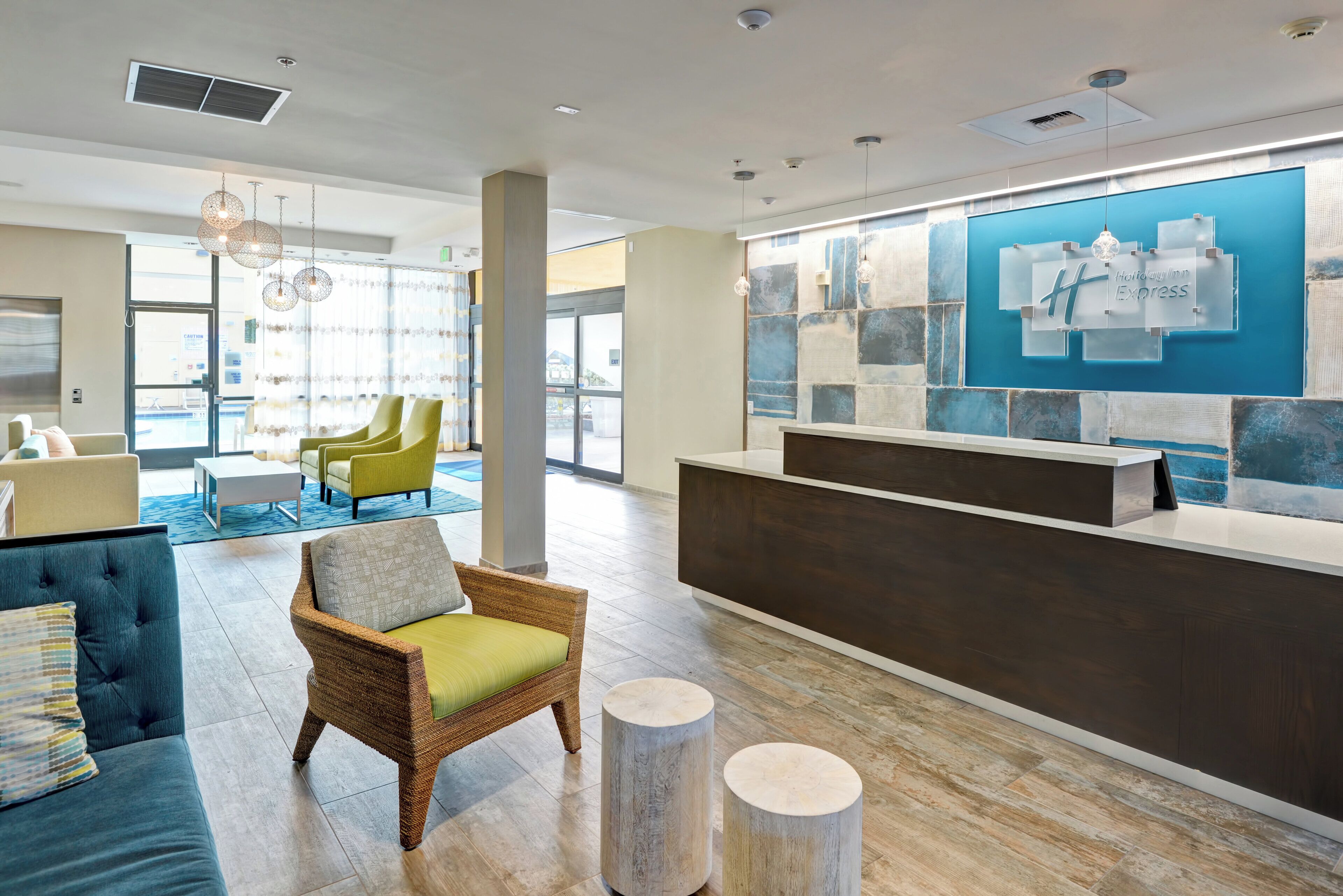 A hotel lobby with a reception desk, seating area, and large windows.
