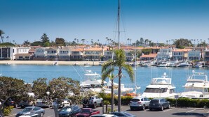 A marina with boats, a parking lot, and buildings with red-tiled roofs.