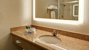 A bathroom with a granite countertop, a sink, a mirror, and a towel rack with folded towels.