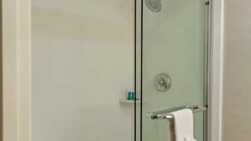 A glass-enclosed shower stall with a white towel hanging on the door handle.