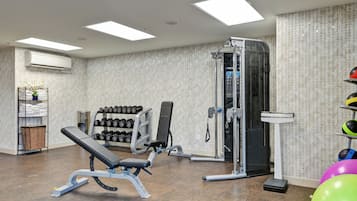 A gym with a bench press, weight racks, a squat rack, and exercise balls.