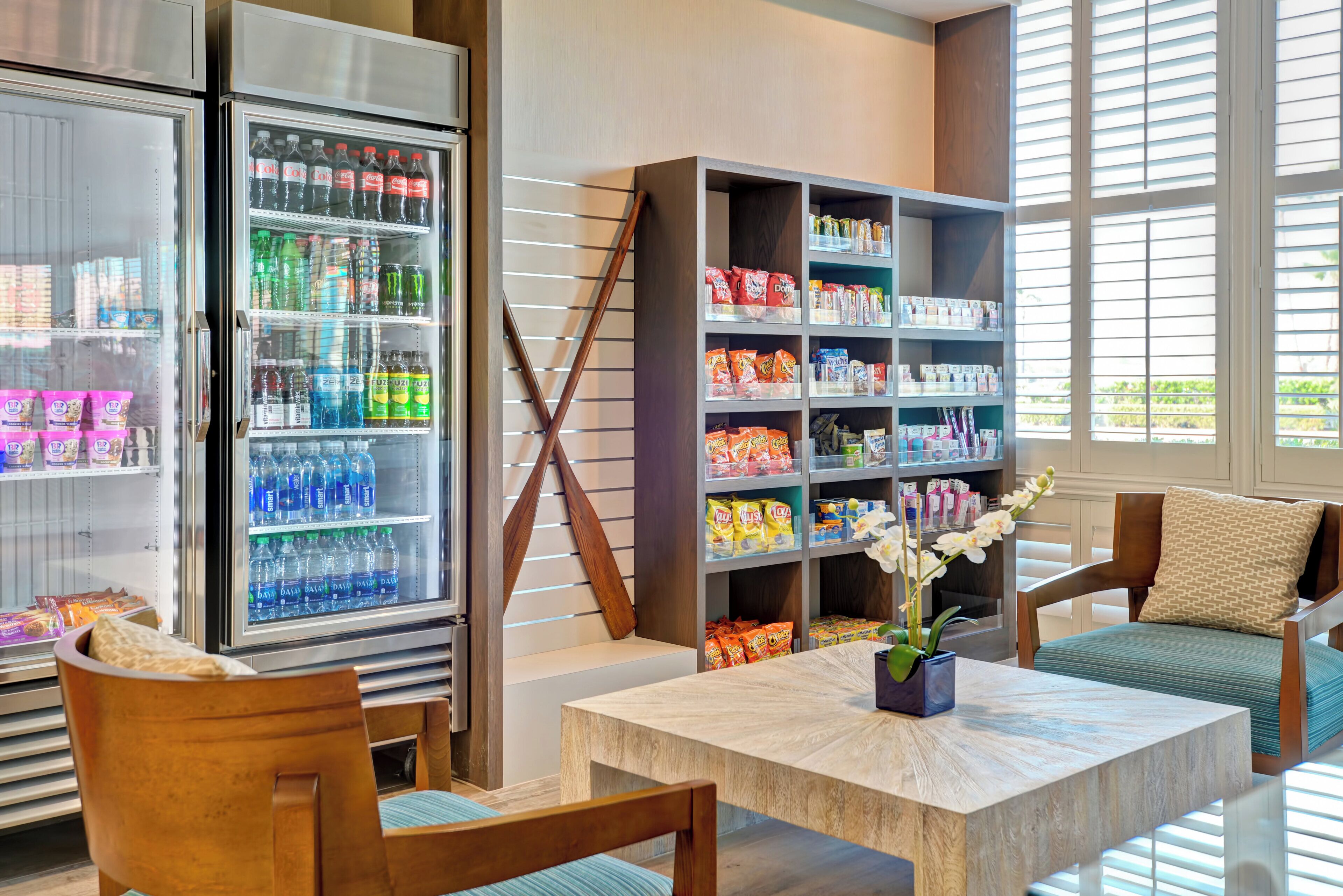 Un vestíbulo de hotel con un área de descanso, un refrigerador de bebidas y una estantería de snacks.