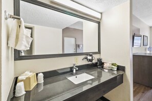 A modern bathroom with a large mirror, a sink, and a towel rack. - Red Roof Inn & Suites Fayetteville - Fort Bragg (Fayetteville)
