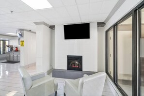 A modern interior with a fireplace, a flat-screen TV, and a seating area with chairs.