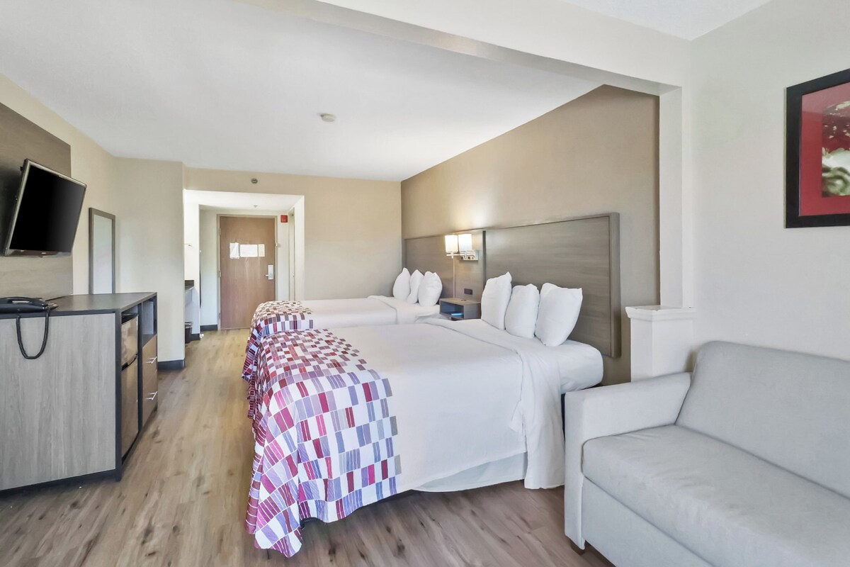 A hotel room with a bed, a desk, a chair, and a television.
