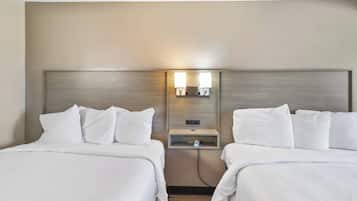 Ein Hotelzimmer mit zwei Betten, jeweils mit weißer Bettwäsche und Kissen. Eine Wandleuchte befindet sich zwischen den Betten.