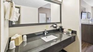A hotel bathroom with a large mirror, a sink, and a towel rack. - Red Roof Inn & Suites Fayetteville - Fort Bragg (Fayetteville)