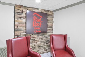 Placa do Red Roof Inn em uma parede de pedra, com duas poltronas de couro vermelho na frente.