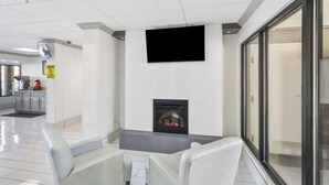A modern interior with a fireplace, seating area, and a flat-screen TV mounted on the wall. - Red Roof Inn & Suites Fayetteville - Fort Bragg (Fayetteville)