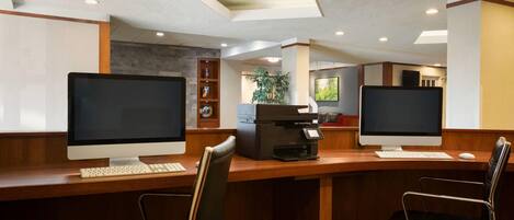A modern office space with two desktop computers, a coffee machine, and ergonomic chairs.
