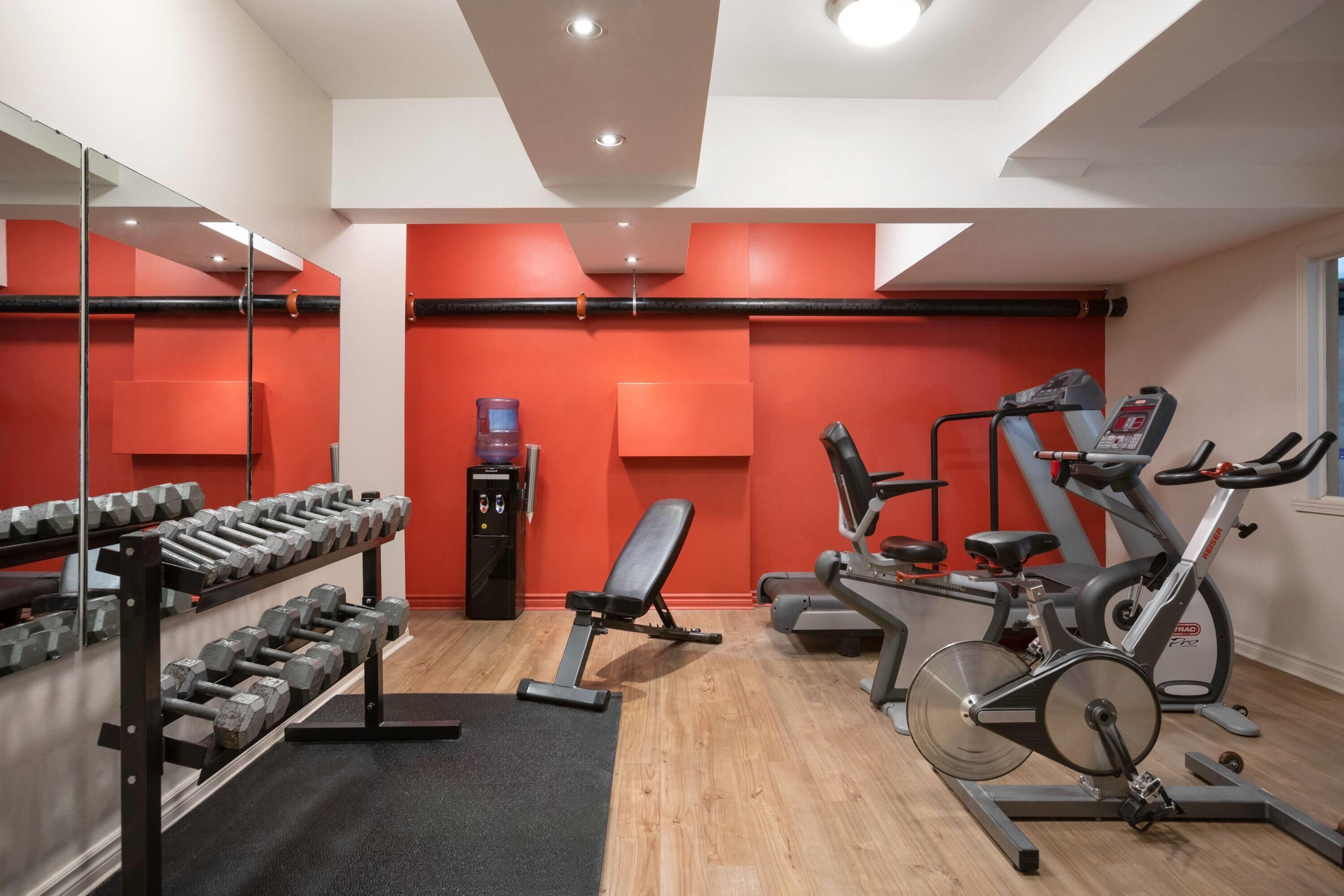 A gym with exercise equipment, a bench, and a water dispenser.