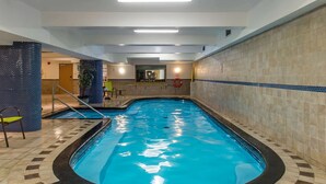 Une piscine intérieure à l’eau d’un bleu limpide, avec des murs carrelés et un poste de surveillance bien visible.