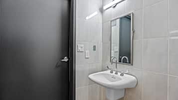 A bathroom with a white sink, a mirror, and a door.