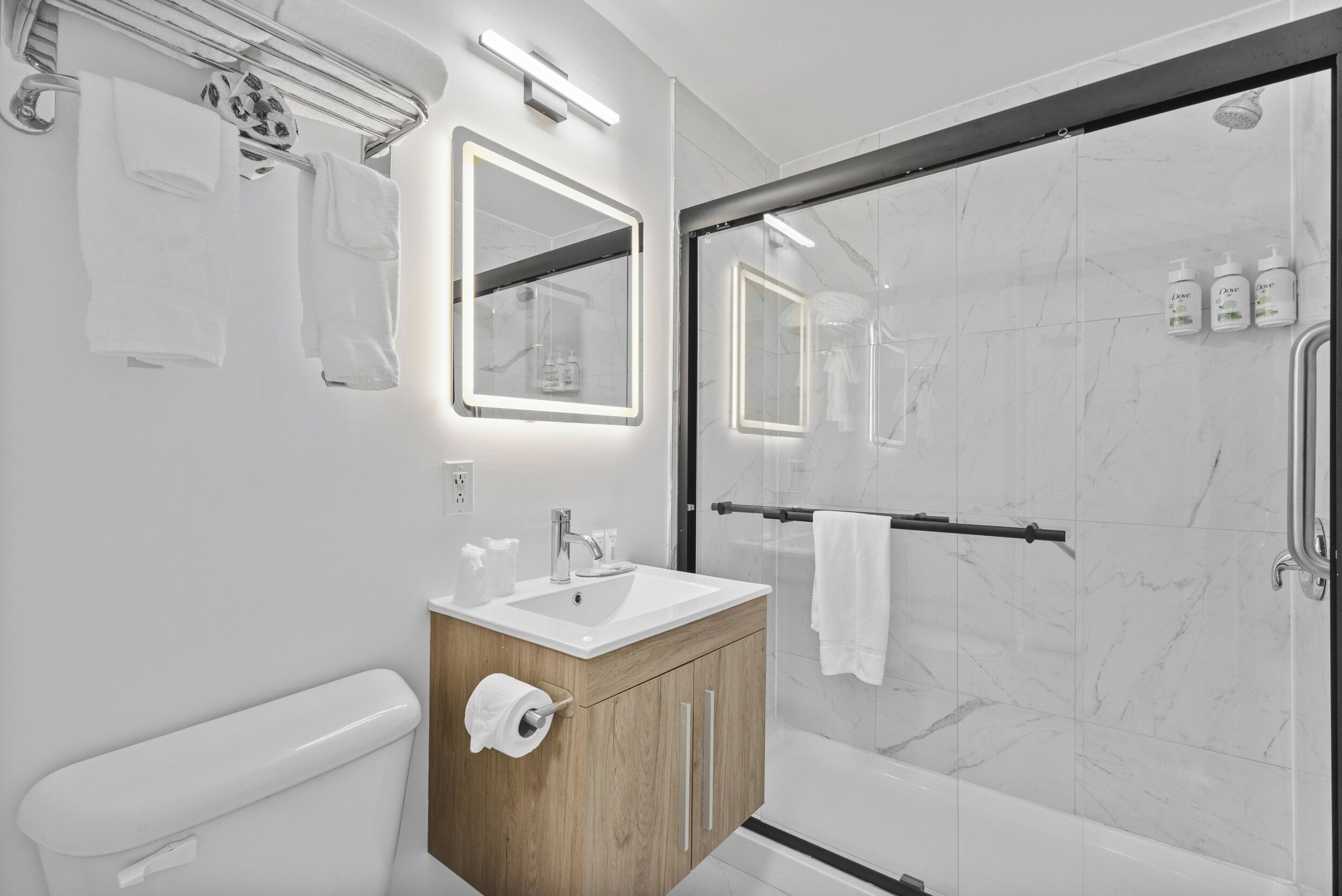 A modern bathroom with a toilet, sink, mirror, and shower.