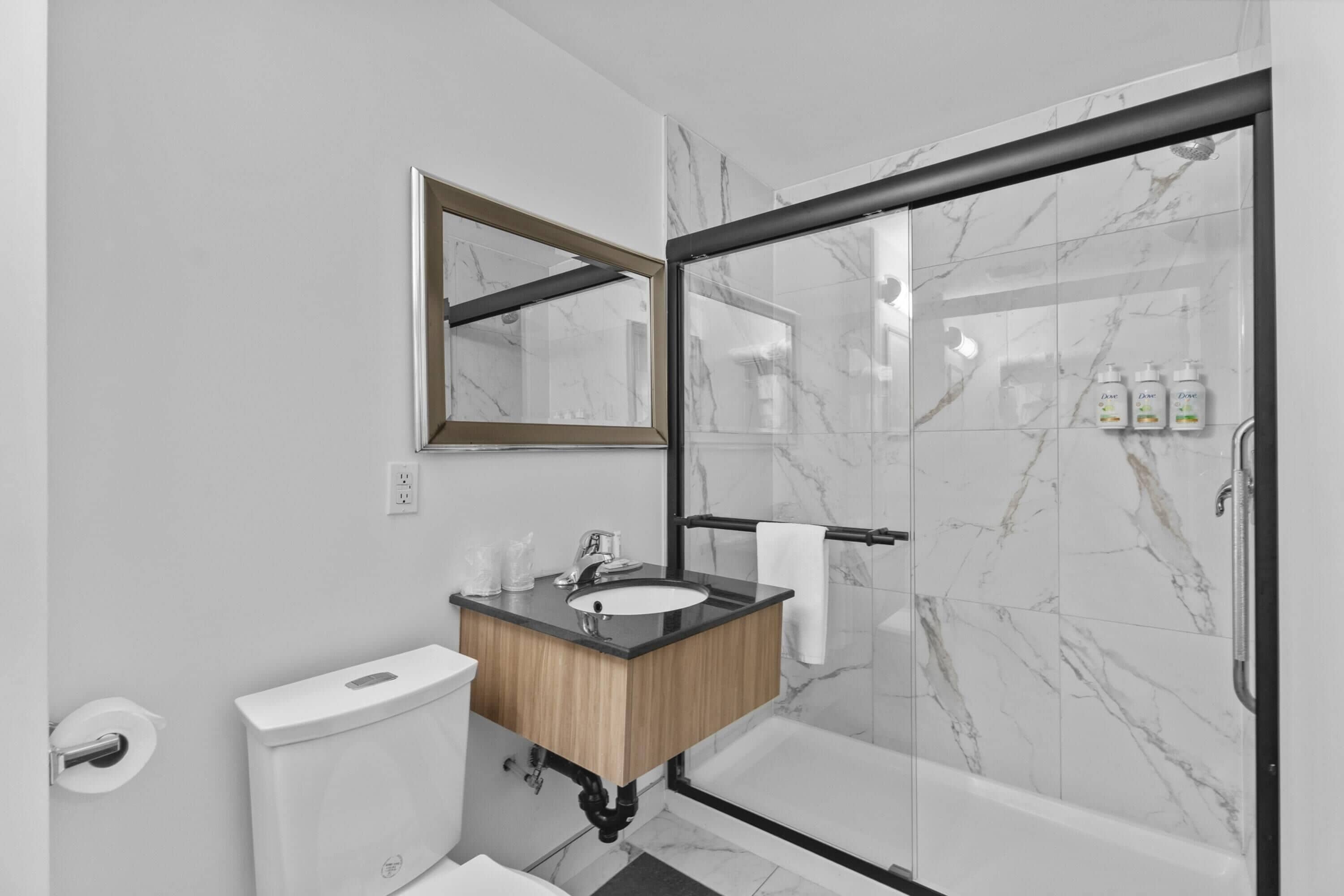 Een moderne badkamer met een douche in marmer, een houten wastafelmeubel en een grote spiegel.