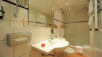 Un baño moderno con lavamanos, inodoro y ducha.