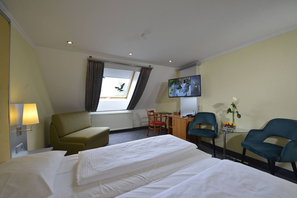 Habitación de hotel con dos camas, un escritorio, una silla, un televisor y una ventana con cortinas.