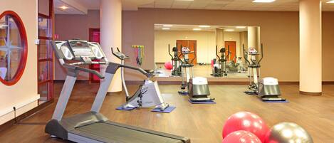 A gym with treadmills, elliptical machines, and exercise balls.