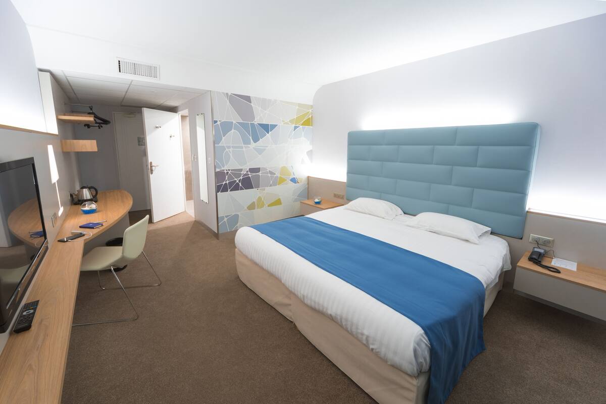 Ein modernes Hotelzimmer mit einem großen Bett, einem Schreibtisch und einem Stuhl.