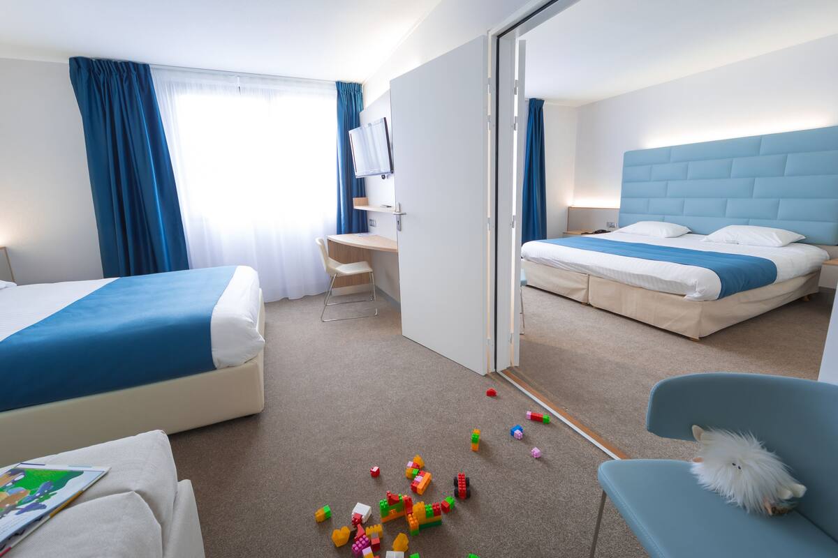 Ein Hotelzimmer mit zwei Betten, einem Schreibtisch und einem Stuhl.