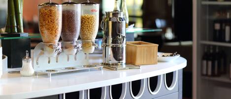 A bar area with a white countertop, three condiment dispensers, a metal coffee pot, and a small wooden box.