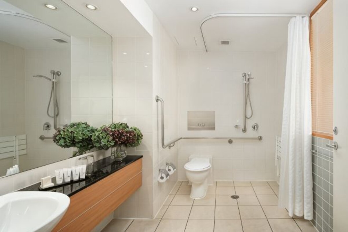 A modern bathroom with a large mirror, a sink, a toilet, and a shower area.