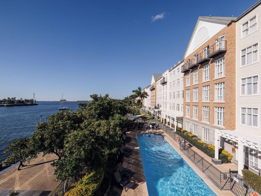 Hotel com piscina adjacente à orla marítima, com varandas e vista para o mar.