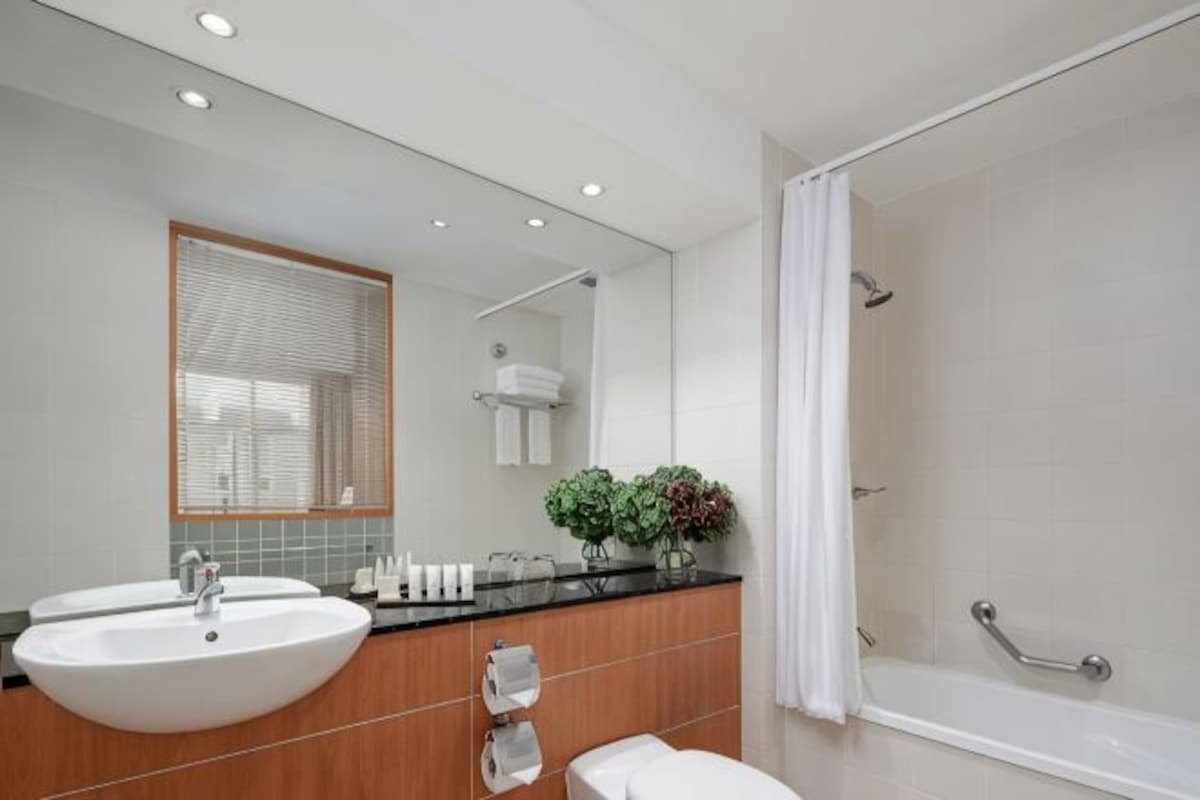 A modern bathroom with a large sink, mirror, and shower.