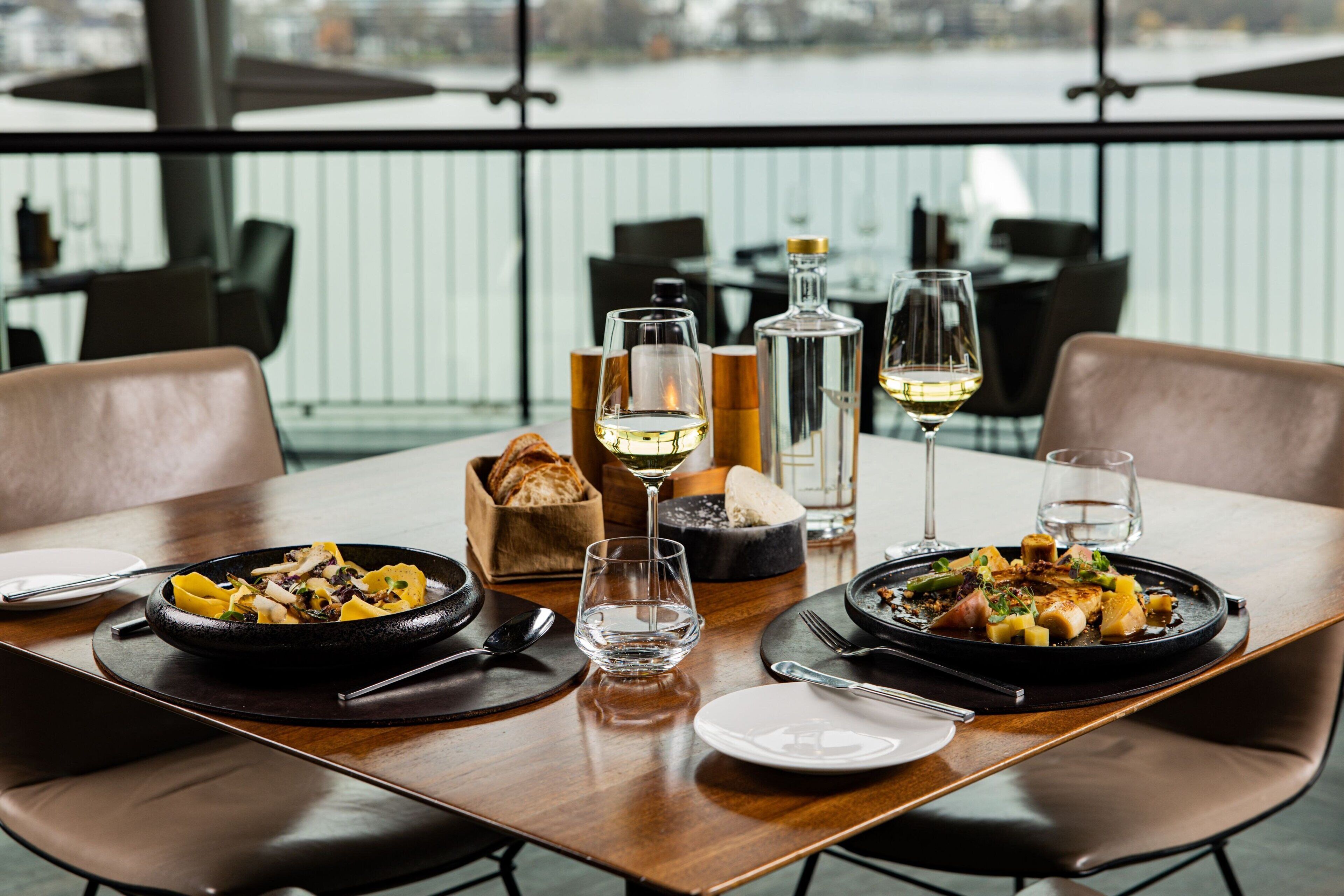 A dining table set with plates of food, glasses, and cutlery.