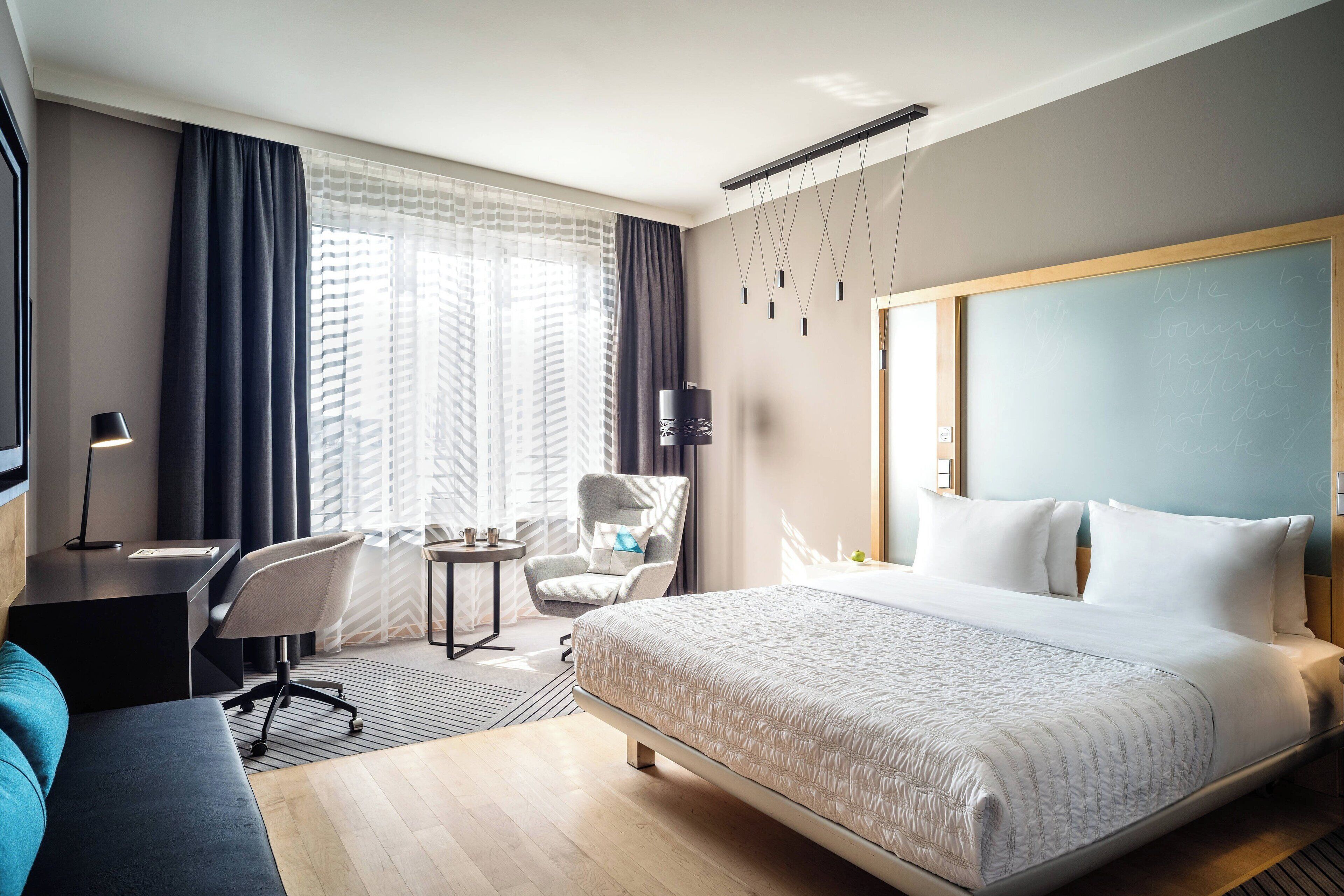 A hotel room with a large bed, a desk, a chair, and a TV.