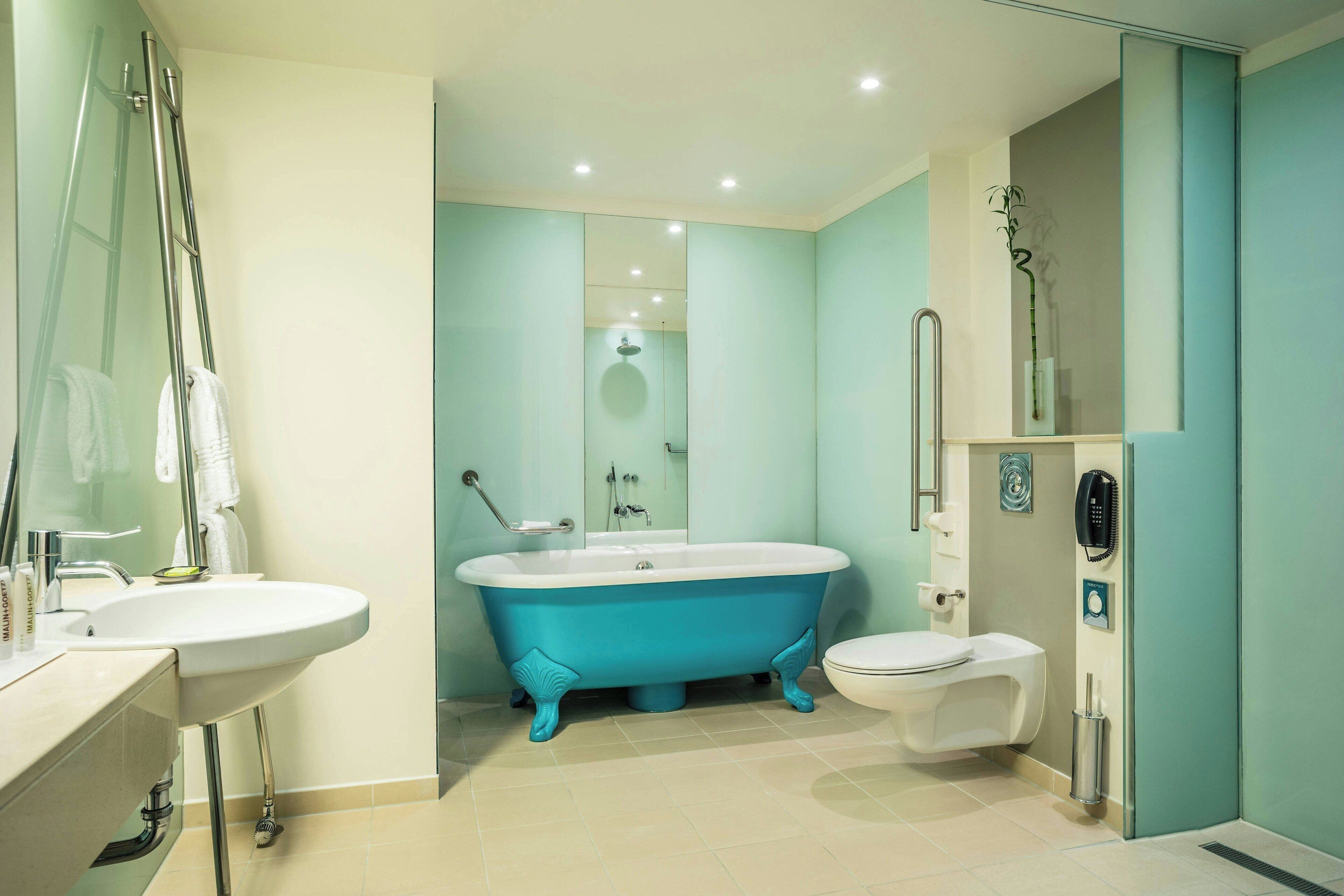 Un baño moderno con una bañera independiente, un inodoro y un lavamanos.
