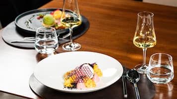 A dining table with a white plate of food, two wine glasses, and a water glass.