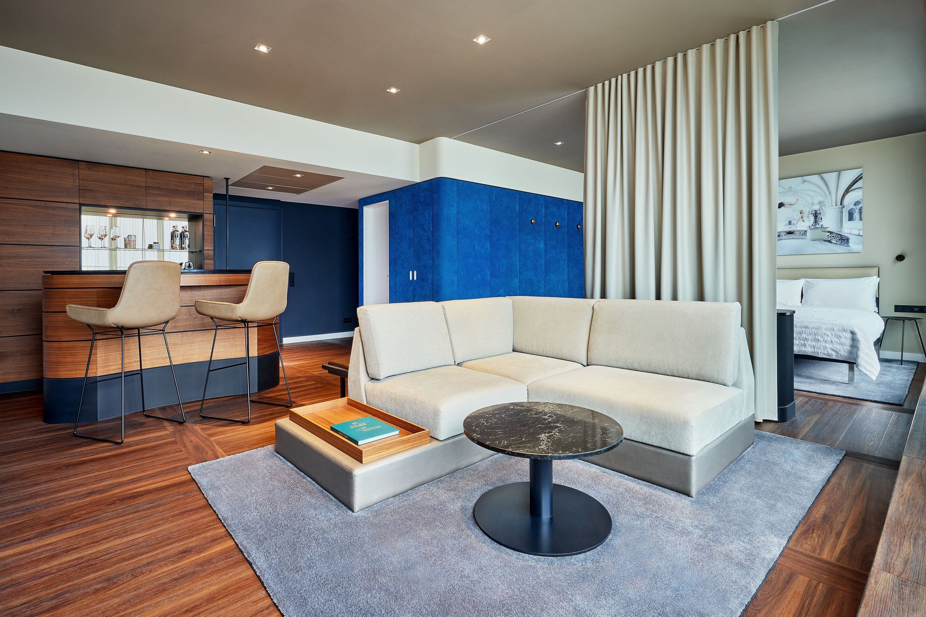 Een moderne woonkamer met een hoekbank, een salontafel en een bar met krukken.
