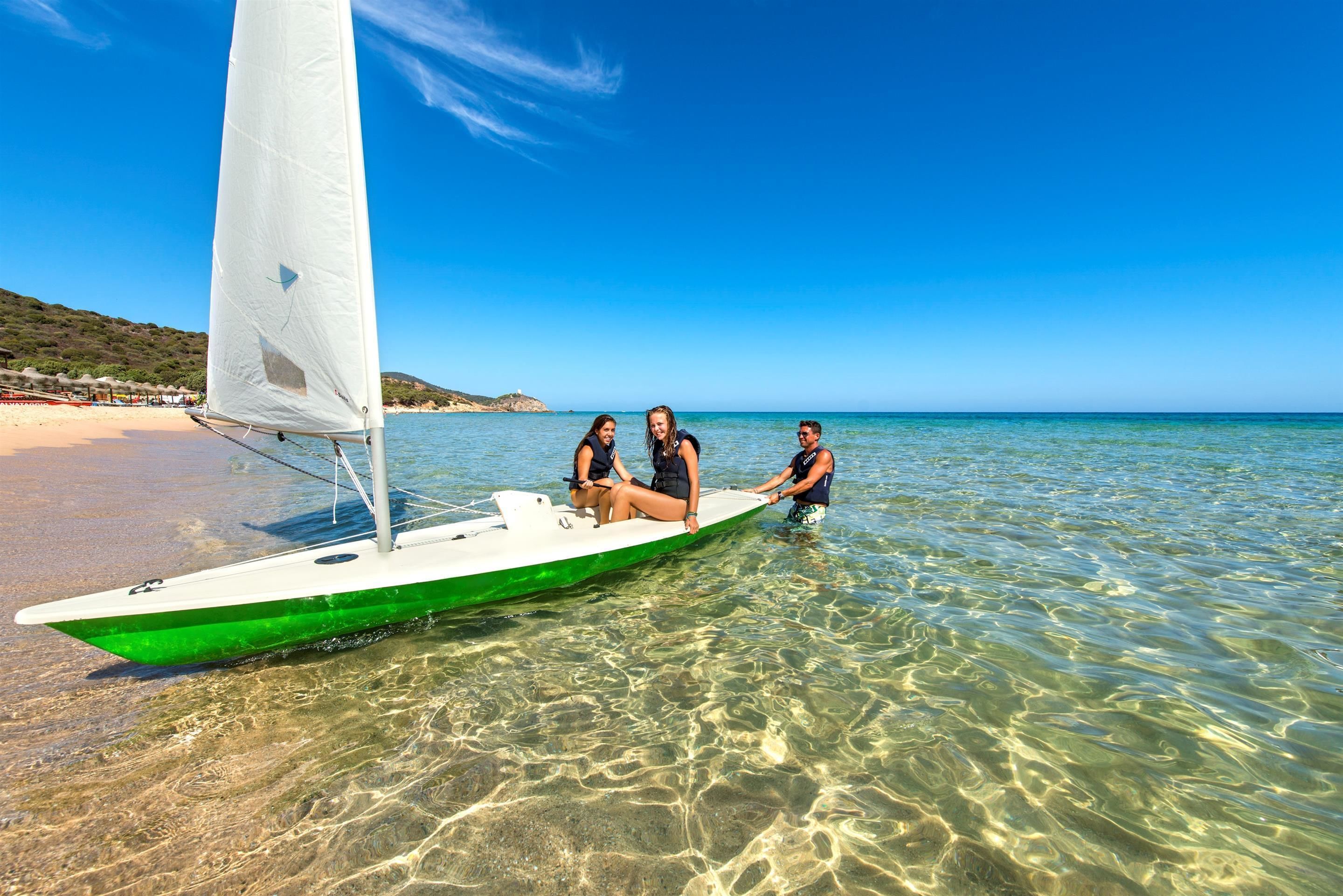 Ein Segelboot mit drei Personen am Strand.