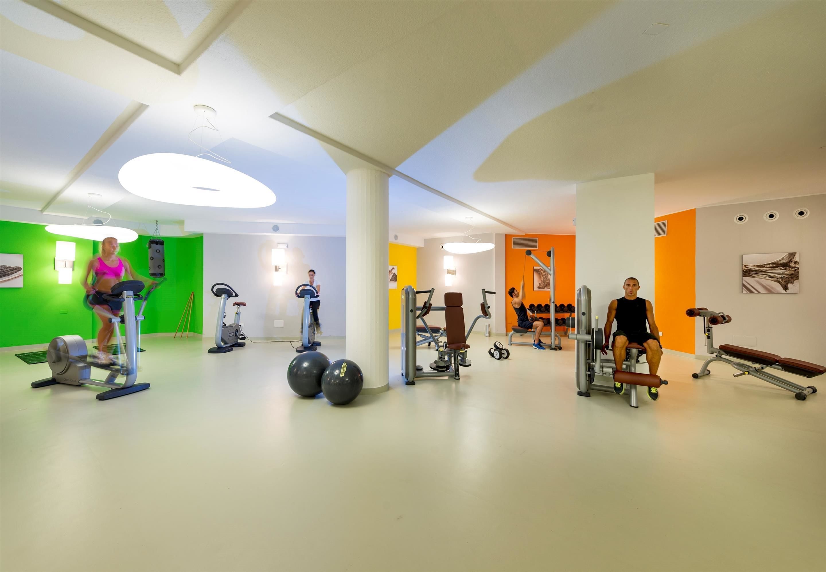Un gimnasio con diversos equipos de ejercicio, incluyendo cintas de correr, bicicletas estáticas y máquinas de pesas.