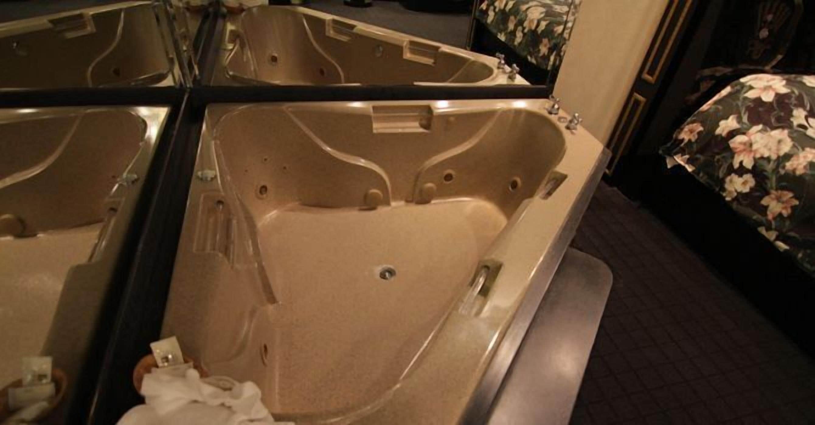 Un baño con una bañera grande, un espejo y una silla con estampado floral.